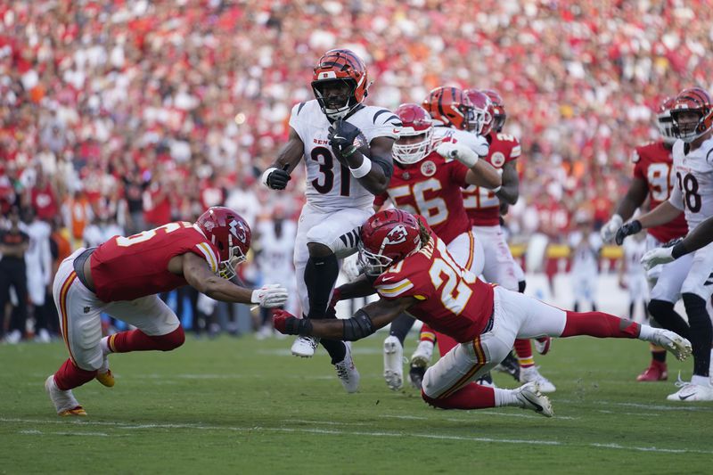 Cincinnati Bengals Zack Moss (31) runs with the ball as Kansas City Chiefs safety Bryan Cook, left, and safety Justin Reid (20) defend during the second half of an NFL football game Sunday, Sept. 15, 2024, in Kansas City, Mo. (AP Photo/Ed Zurga)