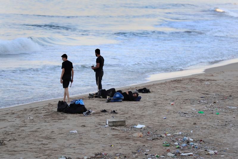 Lebanese men who fled on the southern villages amid ongoing Israeli airstrikes Monday, sleep on a public beach in the southern port city of Sidon, Lebanon, Tuesday, Sept. 24, 2024. (AP Photo/Mohammed Zaatari)