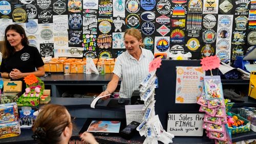 Michelle Rutkowski, owner of Boardwalk Best and Five Mile Marketplace, hands a customer a receipt in Wildwood, N.J., Friday, Aug. 9, 2024. (AP Photo/Matt Rourke)