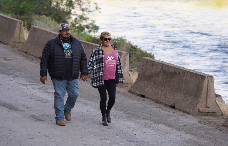 In this image provided by Matthew Johan Mais, Molli Myers and her husband Frankie hold hands as they watch construction crews work to remove the final cofferdam that was left of Iron Gate Dam, allowing the Klamath River to flow through on Aug. 28, 2024, near Hornbrook, Calif. (Matthew Johan Mais via AP)