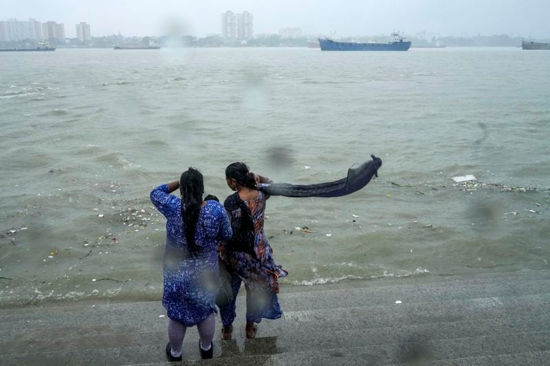 Onlookers watch a raging Hooghly River with high wind in Kolkata, India, as rain continues after cyclone Remal made a landfall near Bangladesh-India border, Monday, May 27, 2024. (AP Photo/Bikas Das)