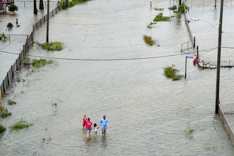 Members of the Vise family walk through the storm surge from Tropical Storm Alberto, Wednesday, June 19, 2024, in Surfside Beach, Texas. They said they needed to get out of their house. ( Jon Shapley/Houston Chronicle via AP)