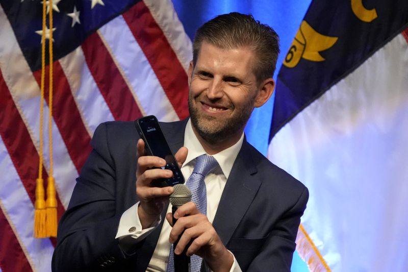Eric Trump holds his phone to the microphone as his father, former President Donald Trump, speaks at the North Carolina GOP convention in Greensboro, N.C., Friday, May 24, 2024. (AP Photo/Chuck Burton)
