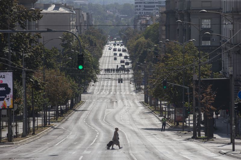 A woman crosses an empty street cordoned off by police during a pride march in Belgrade, Serbia, Saturday, Sept. 7, 2024. (AP Photo/Marko Drobnjakovic)