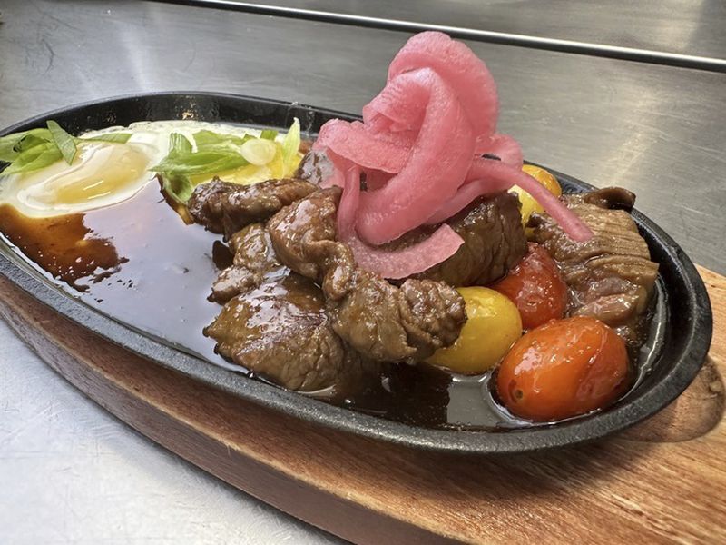 An order of "FO Sizzle,"beef with a sunny side up egg and roasted tomatoes, waits to be taken out of the kitchen at Breaking Dawn restaurant in Los Gatos, Calif., on Sunday, Aug. 4, 2024. (AP Photo/Terry Tang)