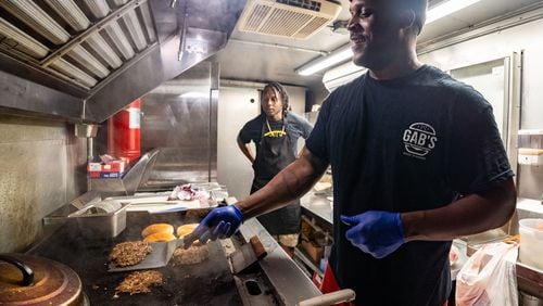 Cornoy Watkins, co-owner of Good As Burgers, prepares vegan burger patties on a grill inside the Good As Burgers food truck outside Bookstore Gallery in Atlanta on Wednesday, July 24, 2024. Due to extreme summer heat, Good As Burgers changed its hours of operation to the evenings. (Seeger Gray / AJC)