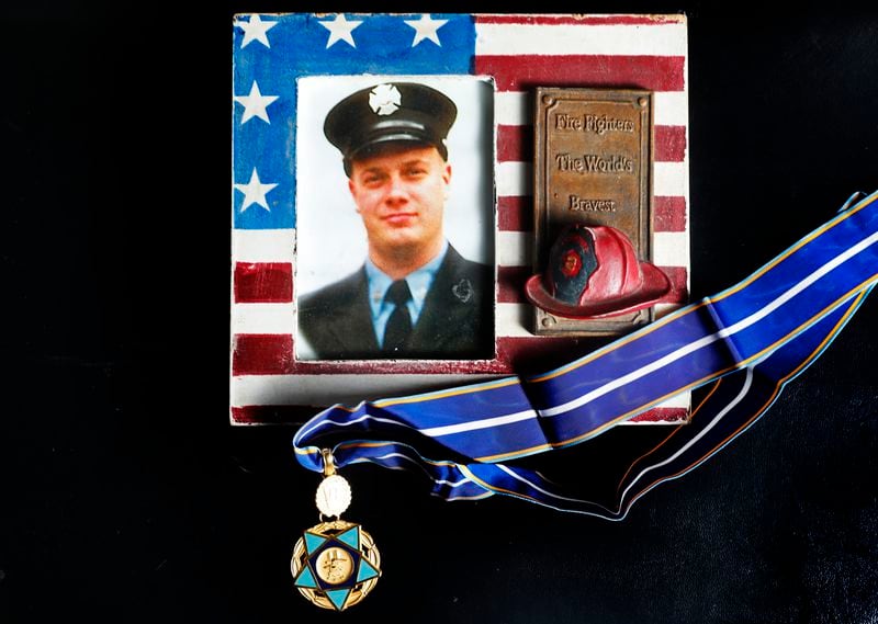 A photo of New York firefighter Christopher Michael Mozzillo, who died in the 9/11 attacks, with his 9/11 Medal of Valor is shown, Saturday, Sept. 7, 2024, in Freehold, N.J.. (AP Photo/Noah K. Murray)