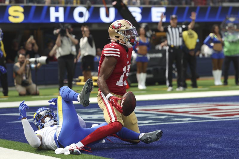 San Francisco 49ers wide receiver Jauan Jennings, middle, reacts after catching a touchdown pass in front of Los Angeles Rams safety Kamren Curl during the first half of an NFL football game, Sunday, Sept. 22, 2024, in Inglewood, Calif. (AP Photo/Ryan Sun)