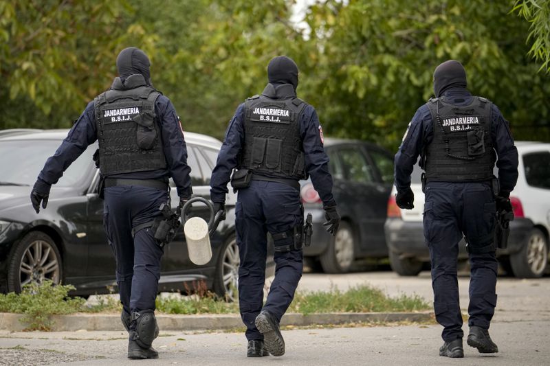 Gendarmes wearing balaclavas hold a battering ram used to break down a door outside the residence of internet influencer Andrew Tate during an early morning police search raid, on the outskirts of Bucharest, Romania, Wednesday, Aug. 21, 2024. (AP Photo/ Vadim Ghirda)