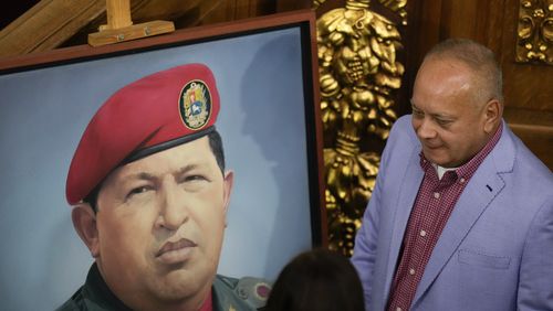 Lawmaker Diosdado Cabello stands next to an image of late President Hugo Chavez in Congress as the National Assembly debates a bill that controls and regulates NGOs, in Caracas, Venezuela, Tuesday, Aug. 13, 2024. (AP Photo/Matias Delacroix)