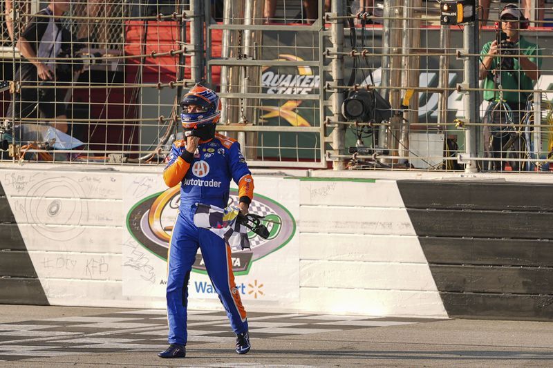 Joey Logano retrieves the checkered flag at the finish line after winning a NASCAR Cup Series auto race Sunday, Sept. 8, 2024, in Hampton, Ga. (AP Photo/Jason Allen)