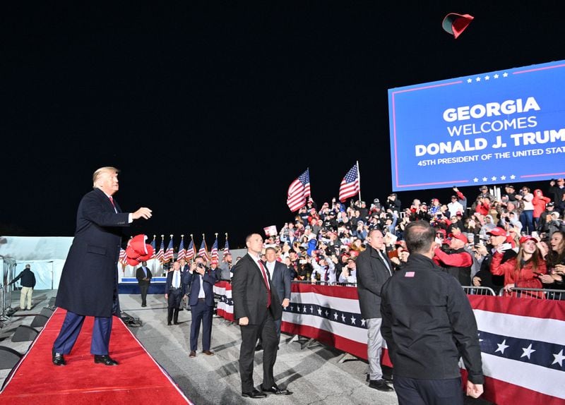Former former President Donald Trump throws hats as he enters the stage during a rally for Georgia GOP candidates at Banks County Dragway in Commerce on Saturday, March 26, 2022. (Hyosub Shin / Hyosub.Shin@ajc.com)