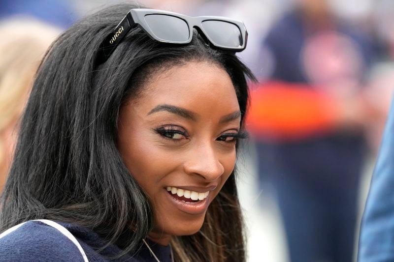 Simone Biles smiles as she standS on the sidelines before an NFL football game between the Chicago Bears and the Los Angeles Rams on Sunday, Sept. 29, 2024, in Chicago. (AP Photo/Nam Y. Huh)