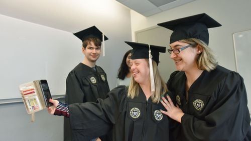 Alex Goodman and Faith Roman (right) pose for a selfie with Kurt Vogel in the background as they try on their caps and gowns ahead of their graduation from the EXCEL program for students with intellectual disabilities at Georgia Tech’s Scheller College of Business.