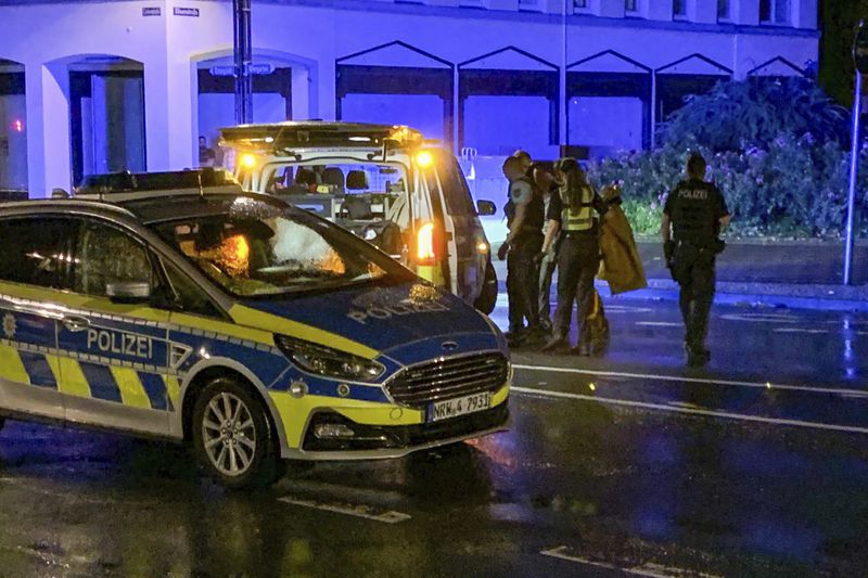 Late in the evening, a man concealed behind police officers turns himself in to the police on the street and claims to be the perpetrator of the attack at a festival in Solingen, Germany, Saturday, Aug. 24, 2024. (Christoph Reichwein/dpa via AP)