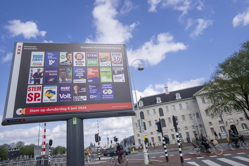 Fietsers passeren een reclamebord voor de Europese verkiezingen buiten het Maritiem Museum in Amsterdam, Nederland, woensdag 5 juni 2024.  De kiezers in de Europese Unie zullen donderdag wetgevers kiezen voor een parlement voor de eerste termijn.  (AP-foto/Peter DeJong)