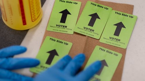 A poll worker sanitizes voting cards during early voting at the Cobb County Elections office in Marietta on Saturday, Dec. 19, 2020. In addition to runoff races for both of Georgia's U.S. Senate seats, a statewide runoff for a Public Service Commission seat is also on the ballot. (Photo: Ben Gray for The Atlanta Journal-Constitution)