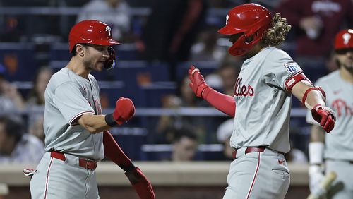 Philadelphia Phillies' Alec Bohm is congratulated by Trea Turner, left, after hitting a three-run home run during the fourth inning of a baseball game against the New York Mets, Friday, Sept. 20, 2024, in New York. (AP Photo/Adam Hunger)