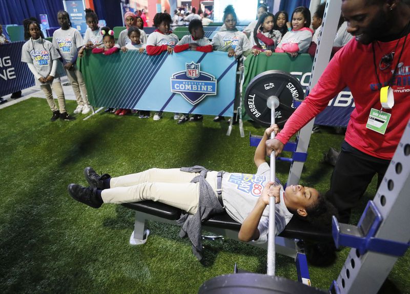 Erin Evans tries her hand at the bench press in the Scouting Combine attraction. NFL PLAY 60 Kids' Day gave more than 2,000 local youth to spend the day at the Super Bowl Experience.  The kids were free to roam through the many attractions at the Georgia World Congress Center. (Bob Andres / bandres@ajc.com)