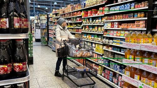 A woman checks prices as she shops at a grocery store in Wheeling, Ill., Friday, Jan. 19, 2024. (AP Photo/Nam Y. Huh)