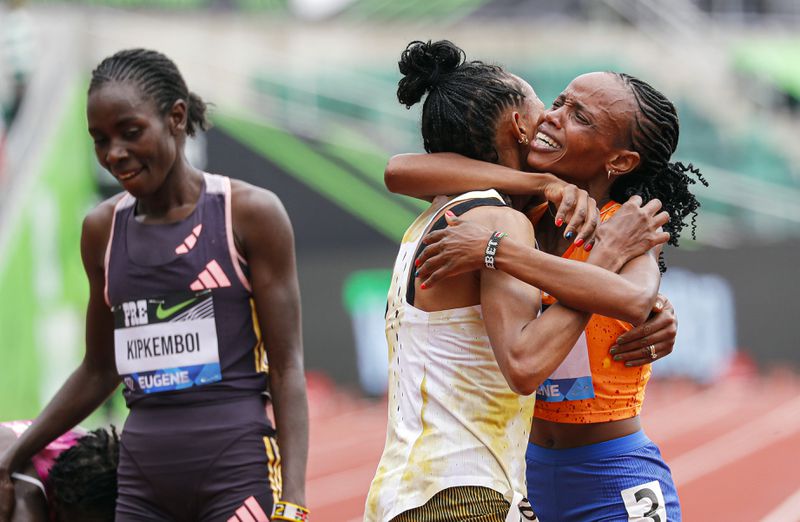 Beatrice Chebet of Kenya, celebrates her world record in the 10,000 with a time of 28:54.14, during the Prefontaine Classic track and field meet Saturday, May 25, 2024, in Eugene, Ore. Gudaf Tsegay, left, of Ethiopia came in second and celebrates with Chebet. (AP Photo/Thomas Boyd)