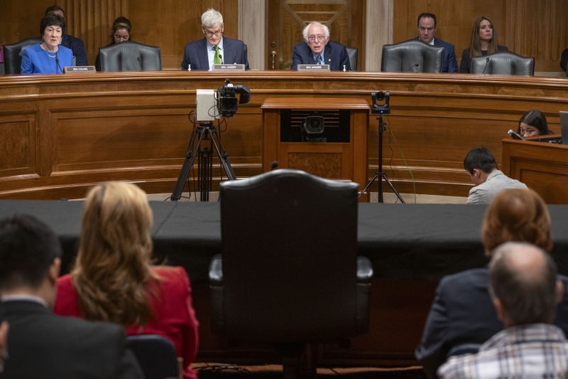 Sen. Bernie Sanders, I-Vt., top center, along with fellow Senators and staff look to the empty chair reserved for Steward Health Care System CEO Ralph de la Torre that sits empty after de la Torre failed to show and testify at a Senate Health, Education, Labor, and Pensions hearing to examine the bankruptcy of Steward Health Care on Thursday, Sept. 12, 2024 on Capitol Hill in Washington. (AP Photo/Kevin Wolf)