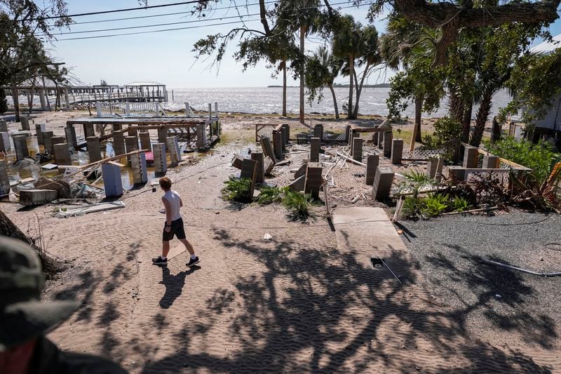 A person walks past building foundations along the water in the aftermath of Hurricane Helene, in Cedar Key, Fla., Friday, Sept. 27, 2024. (AP Photo/Gerald Herbert)