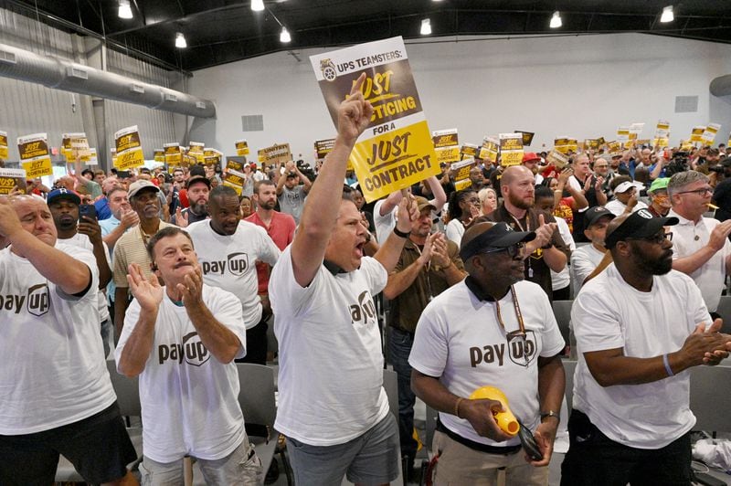 Phil Prince (center) holds a sign to show his support as Teamsters General President Sean O’Brien (not pictured) speaks during a rally just days before high-stakes contract talks with UPS are set to resume, at Teamsters Local 728, Sat. July 22, 2023, in Atlanta. The head of the International Brotherhood of Teamsters revved up the union’s membership in Atlanta at a rally just days before high-stakes contract talks with UPS were set to resume. (Hyosub Shin / Hyosub.Shin@ajc.com)