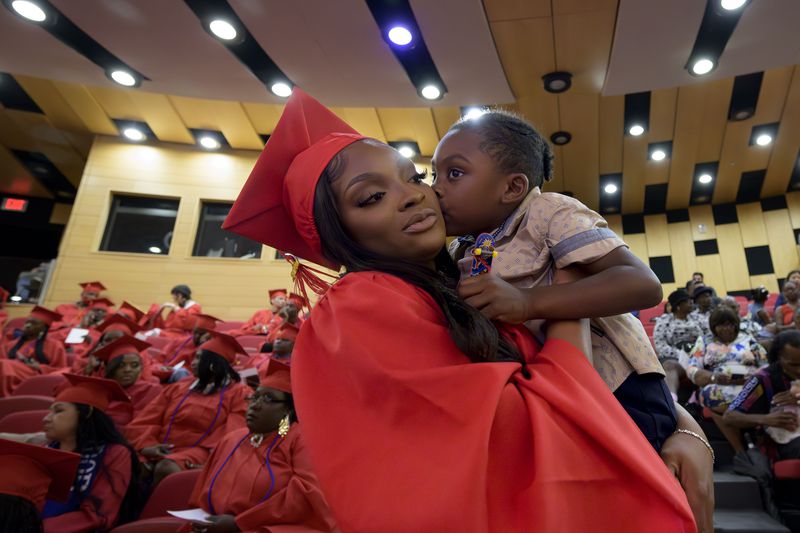 Chamaine Brown holds her son, Kelzie Lewis, 3, before a high school equivalency (HiSET) diploma graduation ceremony for the Youth Empowerment Project (YEP) in New Orleans, Thursday, June 27, 2024. (AP Photo/Matthew Hinton)