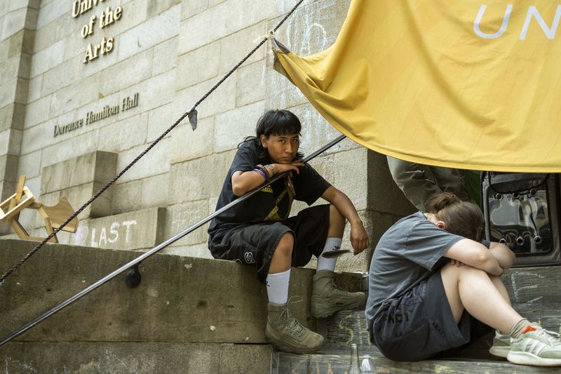 Rising sophomore Michael Pacio Ximio, 19, sits on the steps of Dorrance Hamilton Hall at the University of the Arts, Friday, June 14, 2024, in Philadelphia. Students at the university were thrown into panic mode two weeks ago, as they got the startling news that their school would be shutting down within days. (AP Photo/Joe Lamberti)
