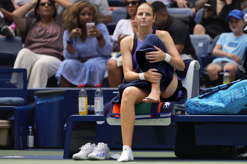 Karolina Pliskova, of the Czech Republic, checks her ankle before retiring against Jasmine Paolini, of Italy, during the second round of the U.S. Open tennis championships, Thursday, Aug. 29, 2024, in New York. (AP Photo/Kirsty Wigglesworth)