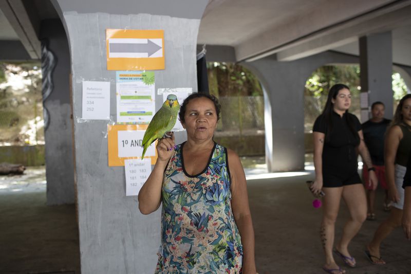 Tereza Domingos holds her parrot Noninho after voting in the municipal elections in Rocinha, Rio de Janeiro, Sunday, Oct. 6, 2024. (AP Photo/Bruna Prado)