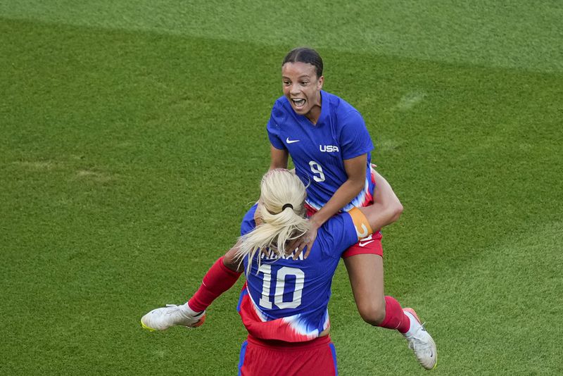 Mallory Swanson leaps into teammate Lindsey Horan's arms.