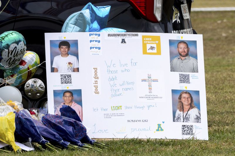 A poster with images of victims Christian Angulo, top left, Richard Aspinwall, top right, Mason Schermerhorn, bottom left, and Cristina Irimie is displayed at a memorial outside Apalachee High School, Friday, Sept. 6, 2024, in Winder, Ga., following a shooting at the school earlier in the week. (Arvin Temkar/Atlanta Journal-Constitution via AP)