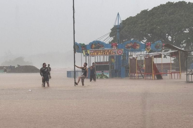 Residents negotiate floods caused by powerful Typhoon Krathon locally called "Typhoon Julian" at Bacarra, Ilocos Norte province, northern Philippines on Monday, Sept. 30, 2024. (AP Photo/Bernie Dela Cruz)