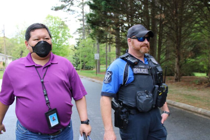 Matthew Dames and Officer Jacob King walk back to their patrol car after checking in with a Cobb County resident they met who had a previous mental health crisis on April 14, 2023. (Photo Courtesy of Madgie Robinson/Fresh Take Georgia)
