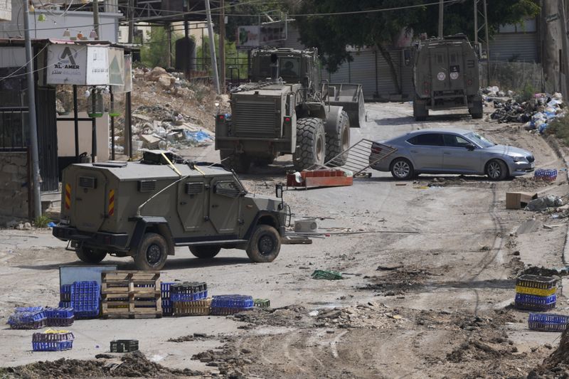 Israeli armoured vehicles move on a street during a military operation in the West Bank refugee camp of Al-Faraa, Wednesday, Aug. 28, 2024. (AP Photo/Nasser Nasser)