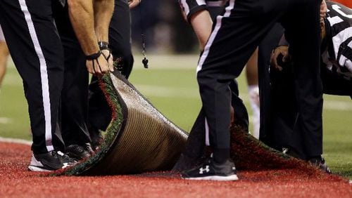 Officials pull up part of the artificial turf in the end zone to examine a during the second half of the Big Ten championship NCAA college football game between Wisconsin and Ohio State , Saturday, Dec. 2, 2017, in Indianapolis. (AP Photo/AJ Mast)