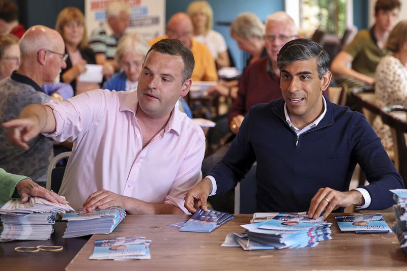 Britain's Prime Minister Rishi Sunak sorts leaflets with Conservative candidate Paul Holmes, as he visits Southern Parishes Conservative Club as part of a Conservative general election campaign event in Hampshire, England, Wednesday July 3, 2024. (Claudia Greco/Pool Photo via AP)