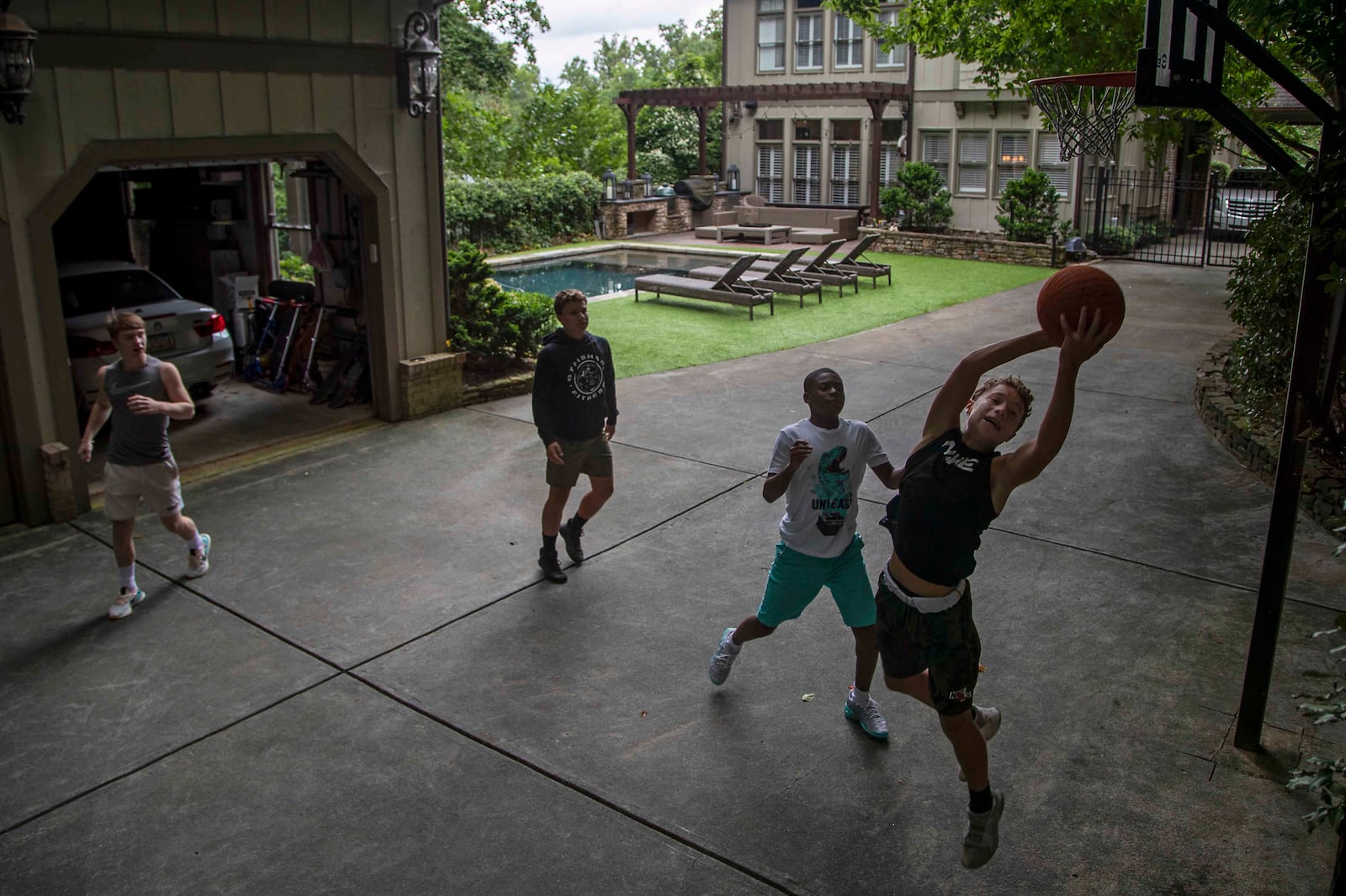 Howard Middle School eighth graders Jack Jenkins (from left), Dean Paulson (second from left), Jahson Jahi (second from right) and Jude Paulson (right) play a pick-up game of basketball during a break in their virtual classes on Friday, August 28, 2020. As part of a learning pod, the boys have the option of playing outside or hanging out in the basement during their breaks. (Alyssa Pointer / Alyssa.Pointer@ajc.com)