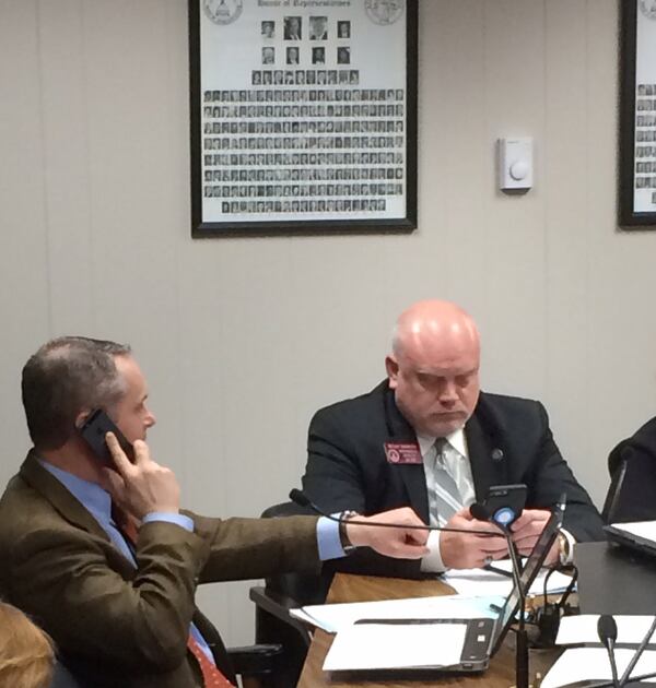 State Rep. Ed Setzler, a Cobb County Republican, demonstrates to his colleagues in a Georgia legislative committee what he won’t be able to do anymore if a distracted driving law is passed. (Photo by Bill Torpy)