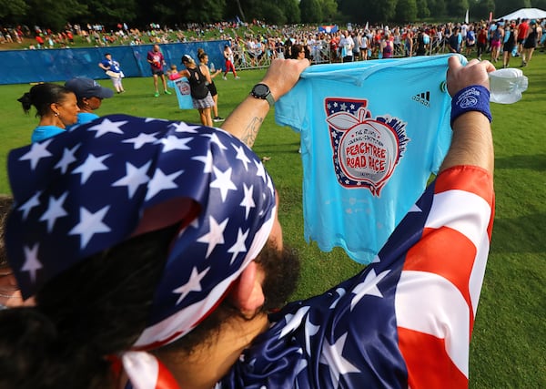 File photo of patriotically dressed runner Steve Boothe, Kennesaw, checks out his hard earned t-shirt after finishing the AJC Peachtree Road Race in Piedmont Park on Monday, July 4, 2022, in Atlanta.  “Curtis Compton / Curtis.Compton@ajc.com”