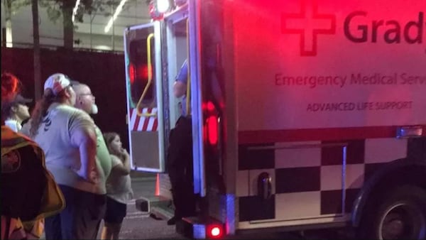 Family members and bystanders look into the ambulance after 11-year-old Kaine Chastain was hit by a car near Mercedes-Benz Stadium, breaking his leg in two places.