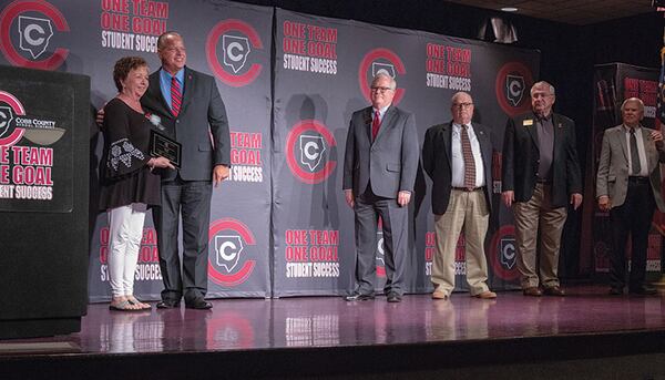 Superintendent Chris Ragsdale stands with a retiring employee as School Board Chair David Chastain and board members Brad Wheeler, Randy Scamihorn and David Banks look on.