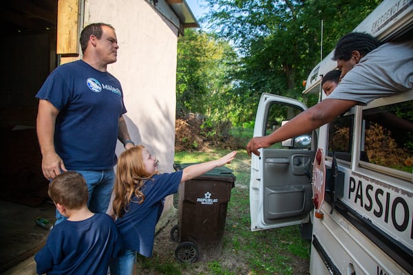 Pastor Terrell Scott and his daughter, Elizabeth, 7, say goodbye to volunteers with the Malachi Project after serving neighbors in the McDonough Housing Authority Complex. PHIL SKINNER/ FOR THE AJC