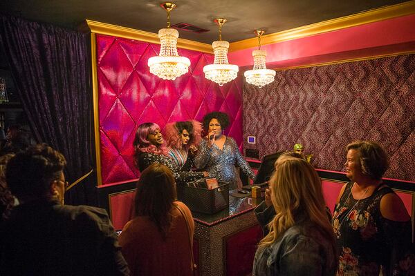 Drag queens Shavonna Brooks (background, from right), Gigi Diamond (background, center) and Lala Ri (background, left), welcome guests in the lobby at Lips in Atlanta. Lips owner Mark “Yvonne Lame” Zschiesche says that television shows like “RuPaul’s Drag Race” have catapulted drag to another level.