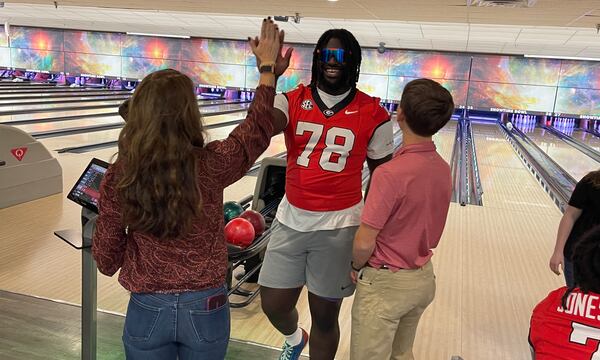 Georgia defensive lineman Nazir Stackhouse high-fives Brittany Thoms of the See.Spark.Go team after scoring a strike in the first annual 'Dawg Bowl' fundraiser for Parkinson's and Crohn's research Wednesday evening at Showtime Bowl in Athens, Georgia. (Chip Towers/chip.towers@ajc.com)