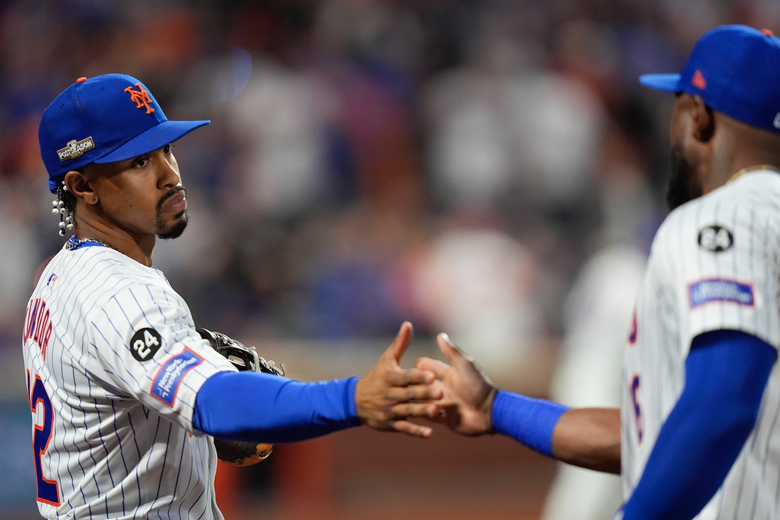 New York Mets shortstop Francisco Lindor (12) greets outfielder Starling Marte (6) in the dugout after a double play against the Philadelphia Phillies during the sixth inning of Game 3 of the National League baseball playoff series, Tuesday, Oct. 8, 2024, in New York. (AP Photo/Frank Franklin II)