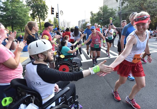 July 4, 2018 Atlanta - Volunteers cheer runners at Cardiac Hill during the AJC Peachtree Road Race on Wednesday, July 4, 2018. HYOSUB SHIN / HSHIN@AJC.COM