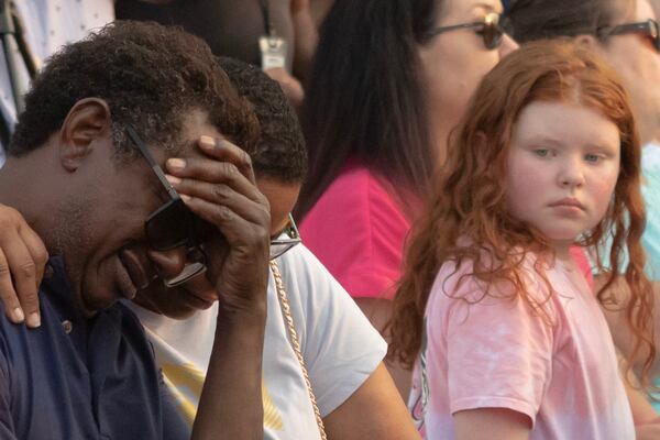 Donald Smith cries while being held by Lima Collins during a Monday candlelight vigil for the victims of last weekend's mass shooting in Hampton. Four people were shot to death in the small south metro Atlanta community. (Michael Blackshire / Michael.Blackshire@ajc.com)